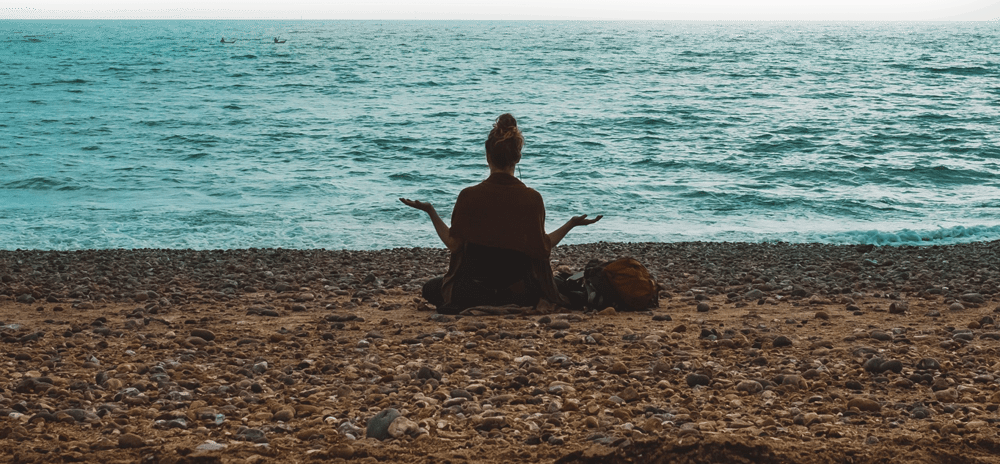 person doing yoga on seashore during daytime